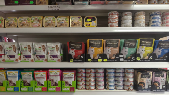 Kaķu barības sortiments veikala plauktos, piedāvājot dažādu zīmolu un veidu produktus mājdzīvnieku uzturam.