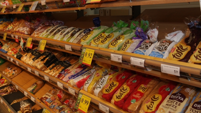 Veikala maizes nodaļas plaukti ar dažādu ražotāju iepakotu baltmaizi.