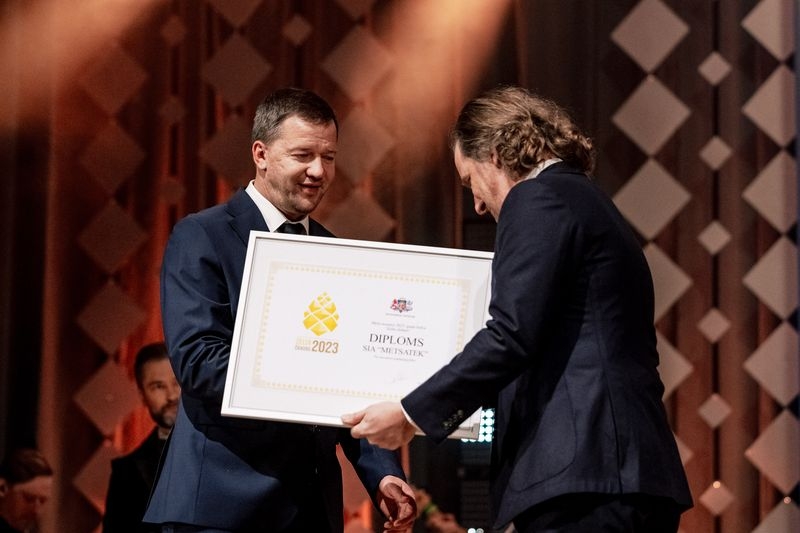 Viens vīrietis otram pasniedz diplomu
