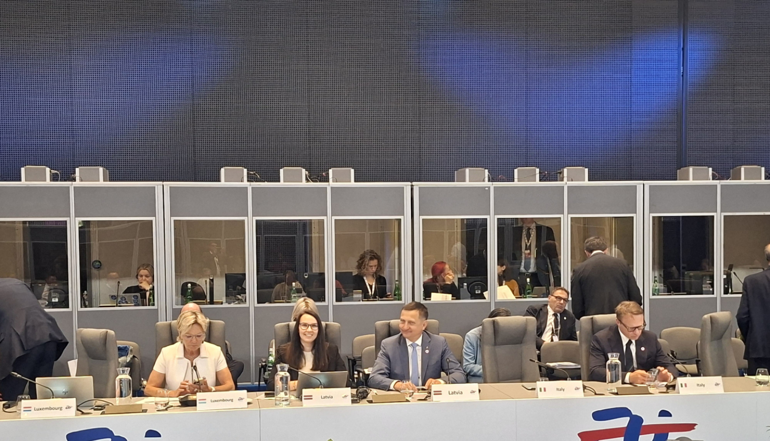 Ministru padome, cilvēki sēž ap galdu ar valstu uzrakstiem