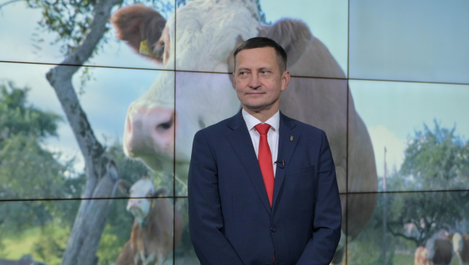 zemkopības ministrs Armands Krauze, fonā uz ekrāna lauku aiva ar govīm