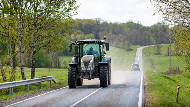 Lielgabarīta traktors brauc pa ceļu