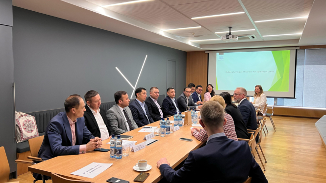 Delegācijas apspriež dokumentus, sēžot ap galdu