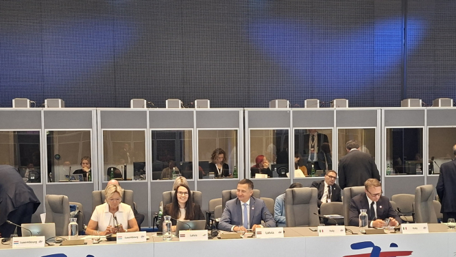 Ministru padome, cilvēki sēž ap galdu ar valstu uzrakstiem