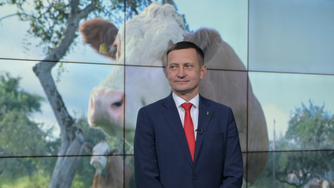 zemkopības ministrs Armands Krauze, fonā uz ekrāna lauku aiva ar govīm