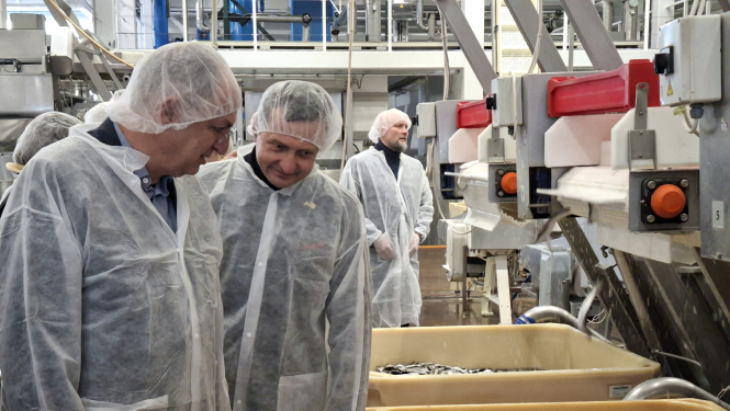 vairāki vīrieši baltos aizsargtērpos zivju pārstādes uzņēmumā