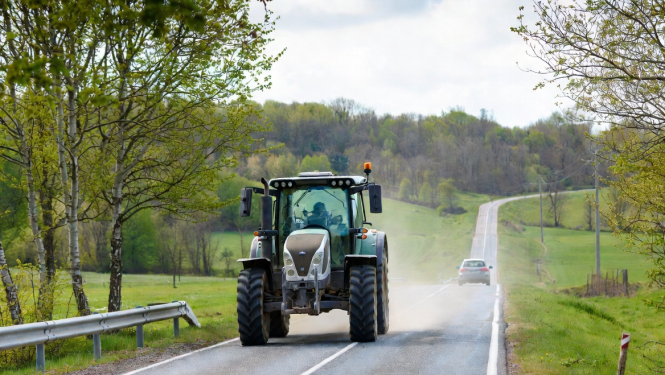 Lielgabarīta traktors brauc pa ceļu