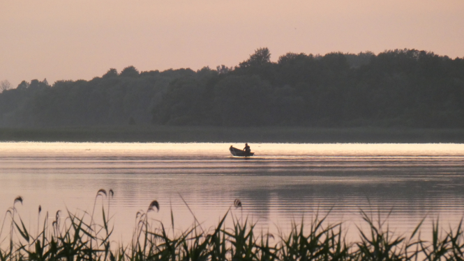 Laiva ezerā un makšķernieks 