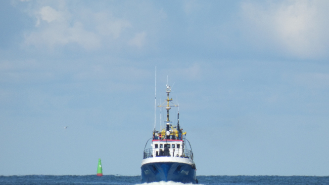 zvejas kuģis no jūras nāk uz ostas pusi