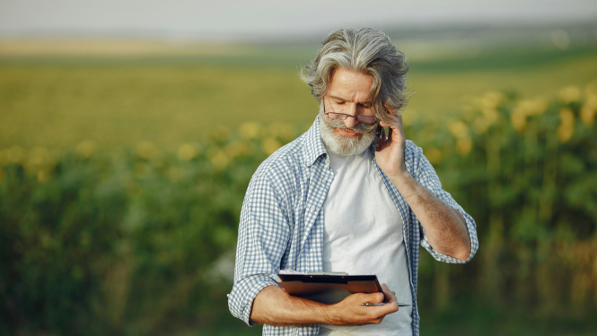 Lauka vidū stāv vīrietis ar planšeti un pildspalvu