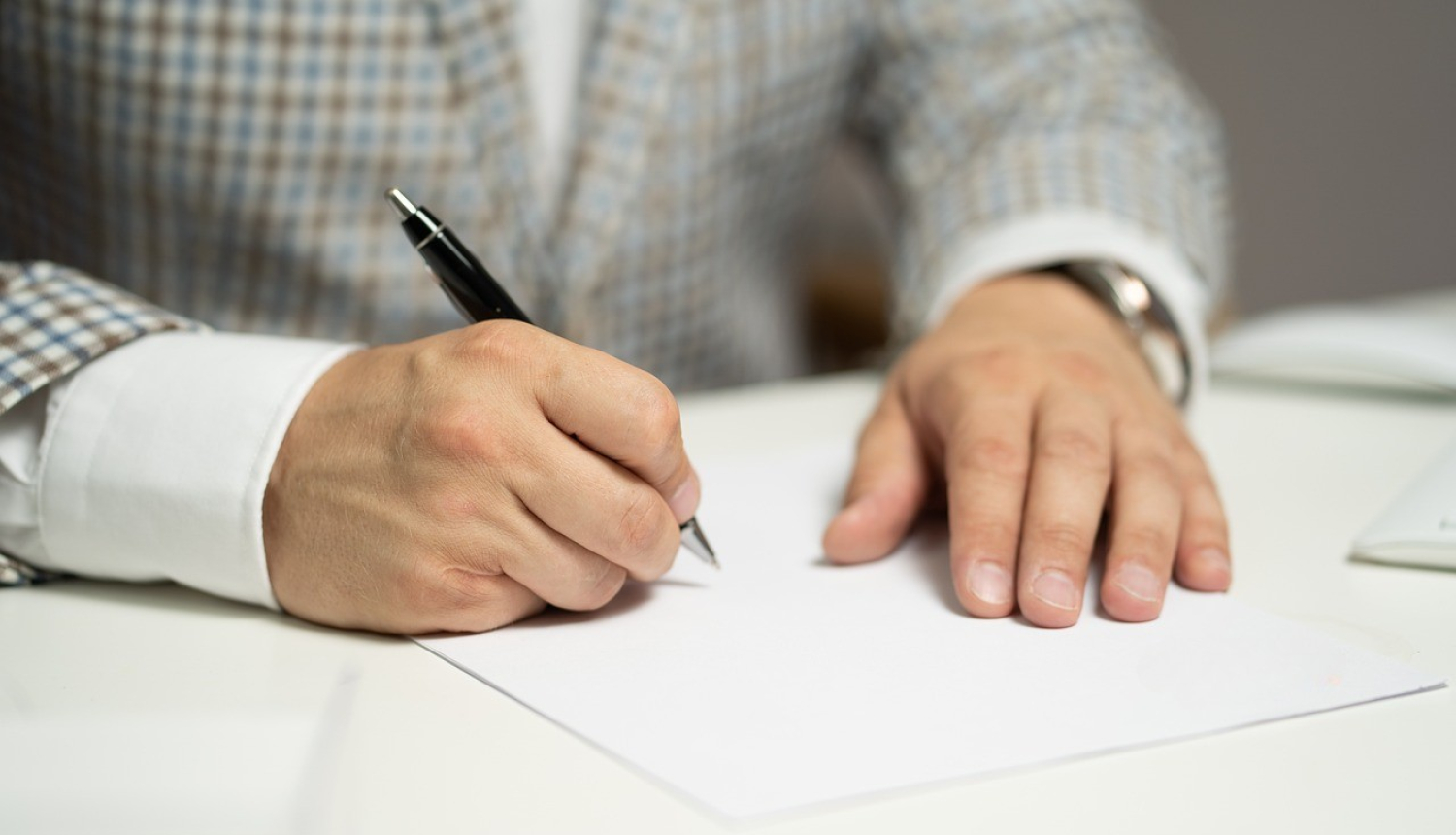 Cilvēks raksta uz baltas lapas