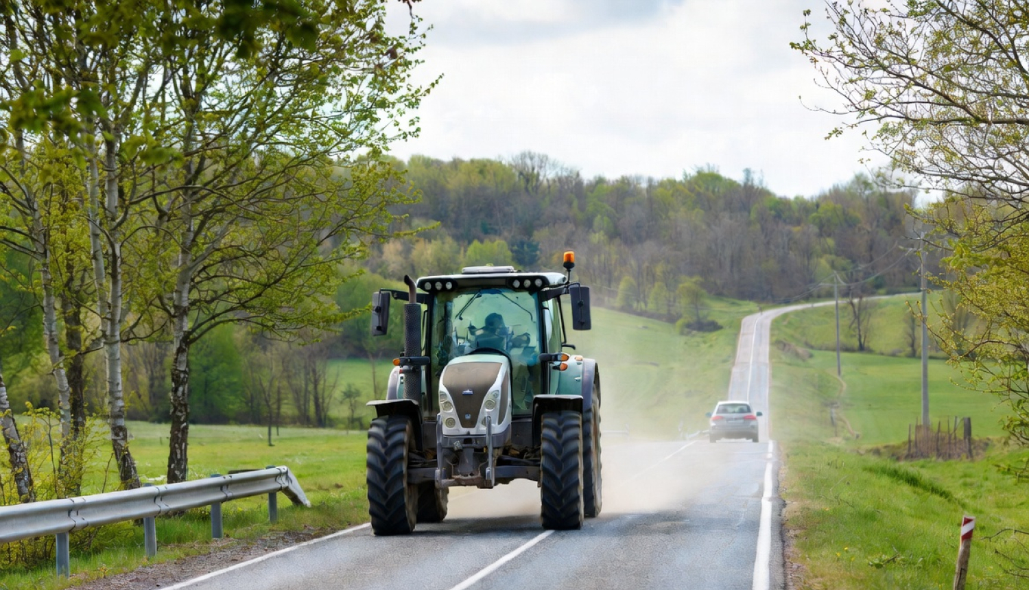 Lielgabarīta traktors brauc pa ceļu