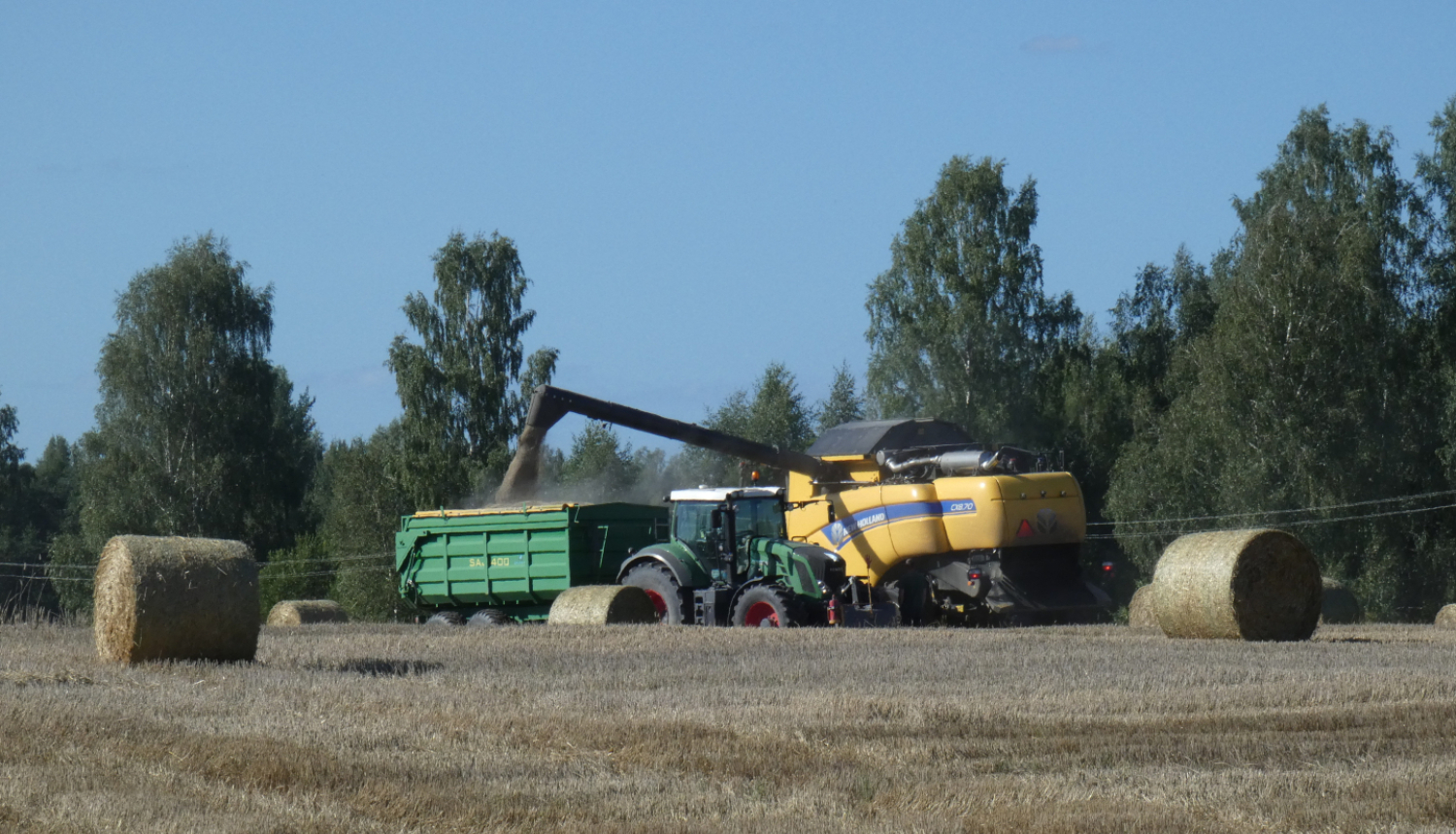 Druvā kombains novāc graudu ražu, iekrauj traktora piekabē. 