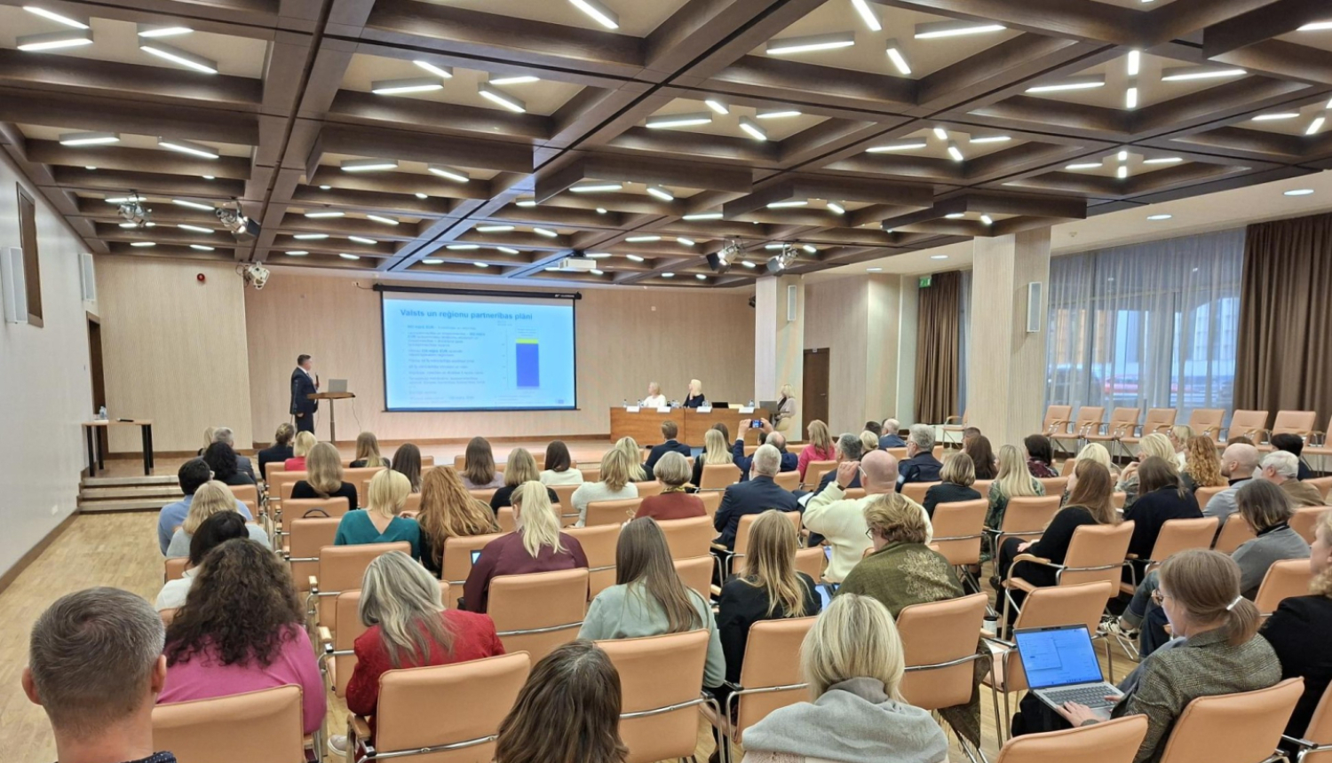 Cilvēki sanāksmē, liela zāle at ekrānu.