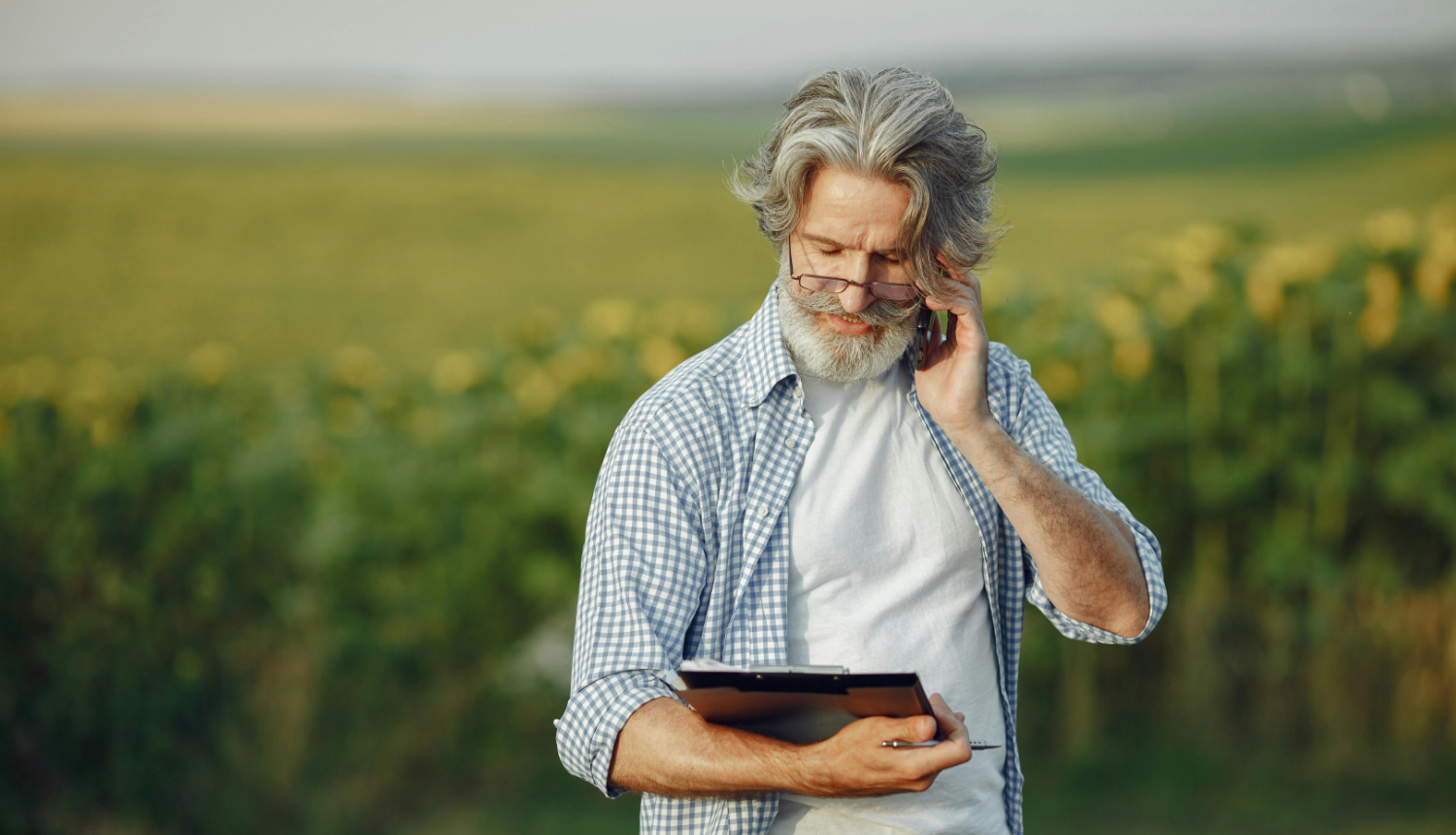 Lauka vidū stāv vīrietis ar planšeti un pildspalvu