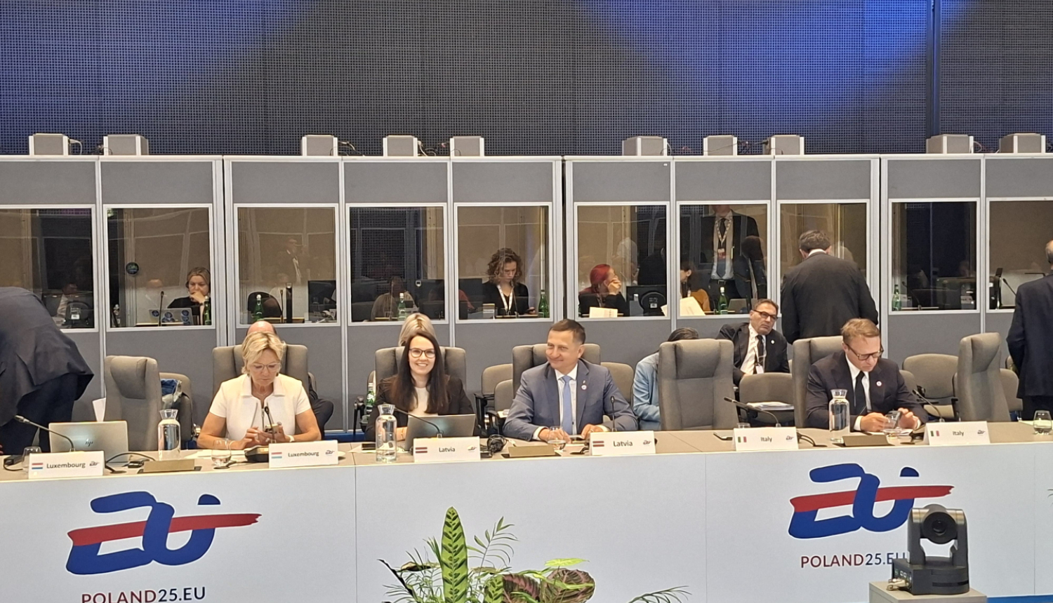 Ministru padome, cilvēki sēž ap galdu ar valstu uzrakstiem
